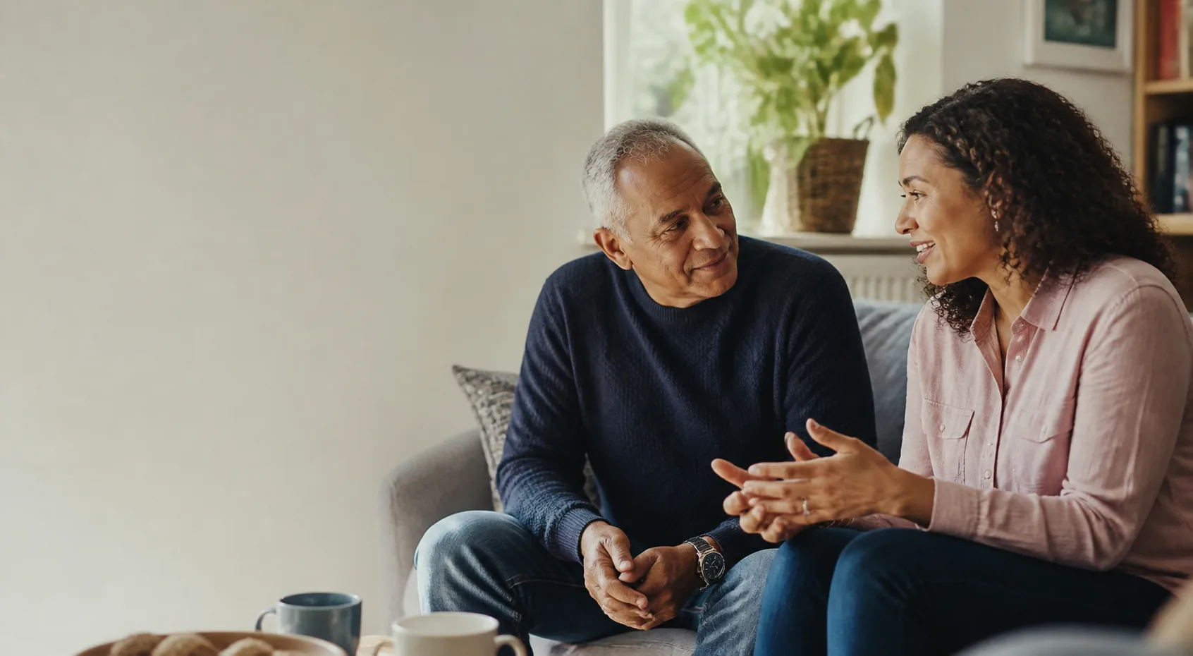 An adult daughter and her older father having a warm conversation at home
