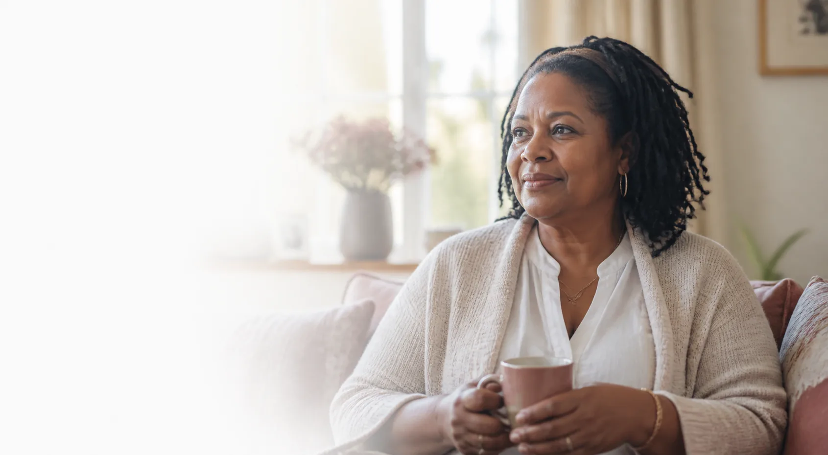 A Black woman relaxing with a mug in a softly lit living room